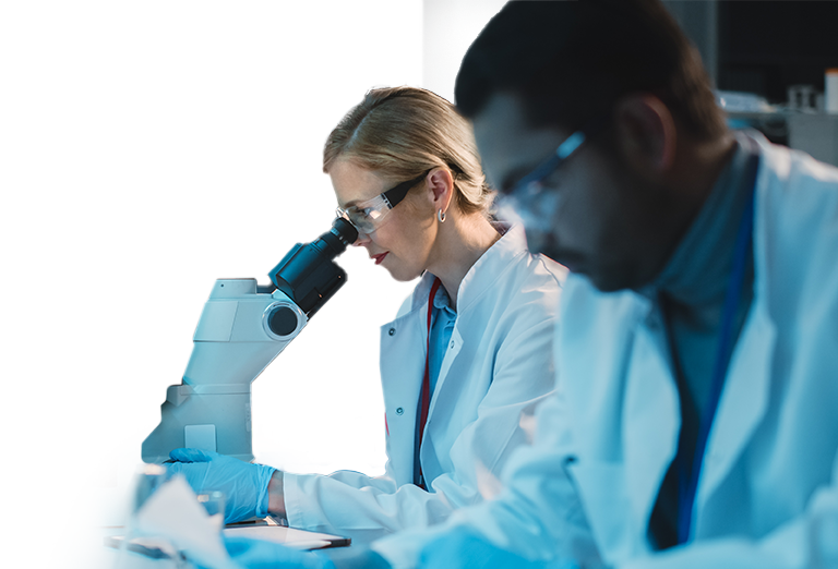 Woman looking into a microscope with man standing next to her